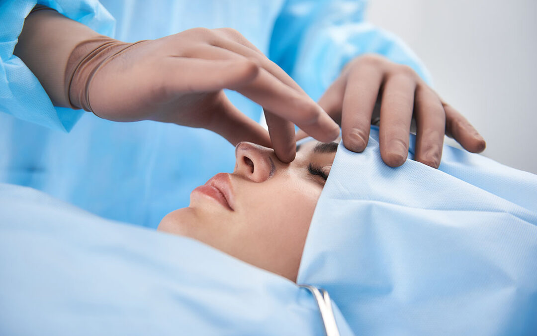 Surgeon in rubber gloves making rhinoplasty for a woman patient
