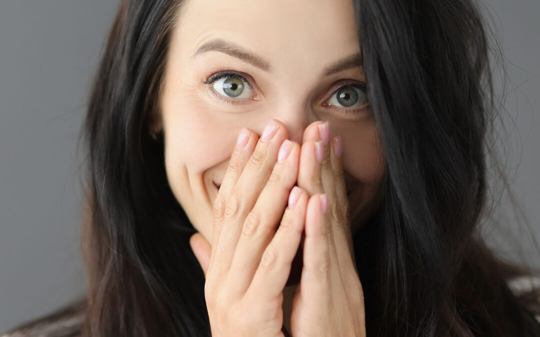 Portrait of smiling young woman covering nose with hand