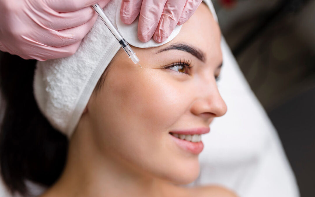 Close up of hands of young cosmetologist injecting botox in female face