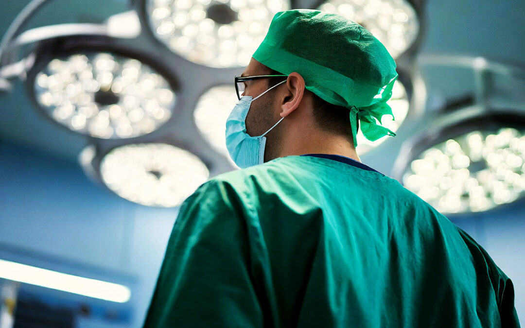Closeup and back view of a male surgeon wearing surgical mask on in operating room at hospital